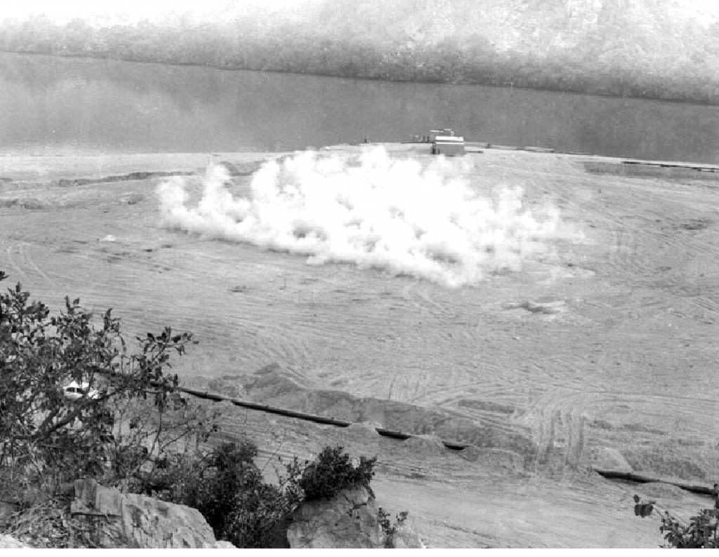 Surface expression of detonation of many charges for deep densification of loose sand at depth.(Photograph from Montreal Engineering Co. Jebba Dam project file, courtesy of AMEC) Surface expression of detonation of many charges for deep densification of loose sand at depth.(Photograph from Montreal Engineering Co. Jebba Dam project file, courtesy of AMEC)