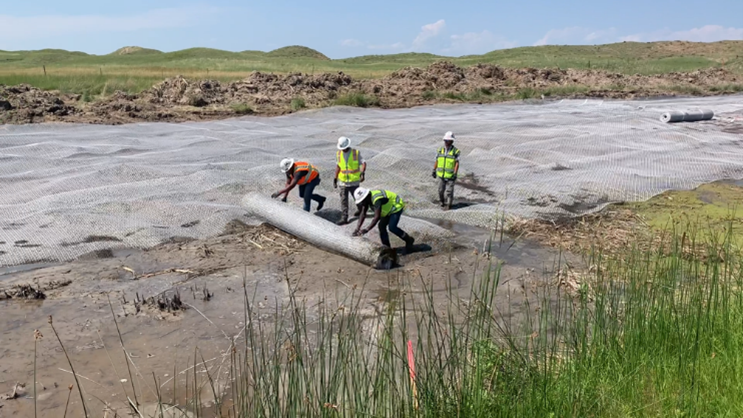 Photograph of rolling out geogrid on subgrade. 