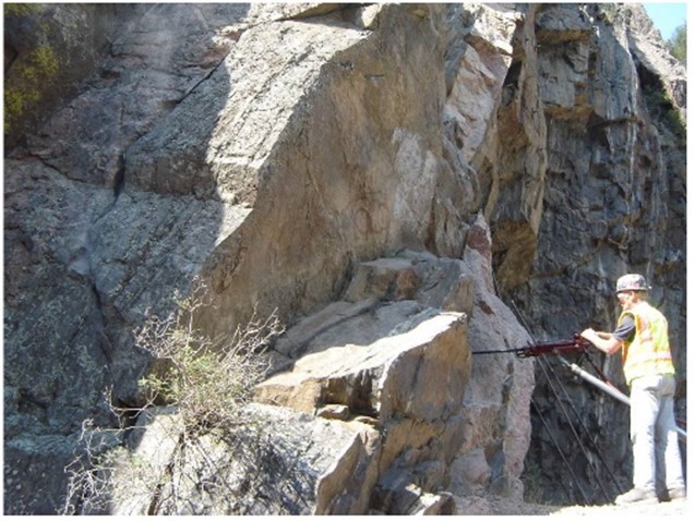 Worker drilling into the rock face for resin injection. 